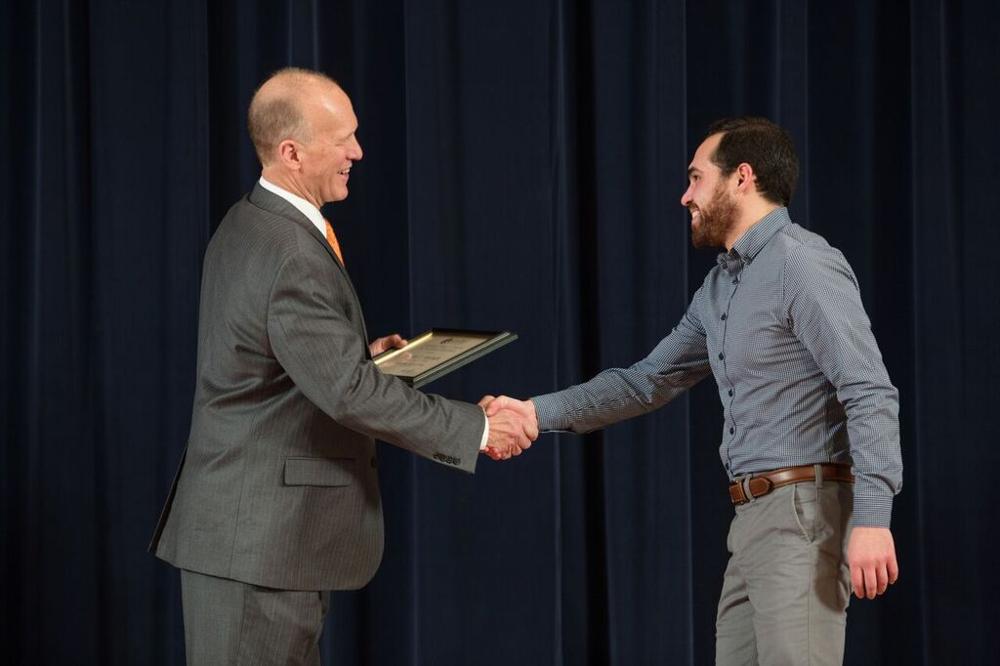 Doctor Potteiger shaking hands with an award recipeint with a blue patterned shirt